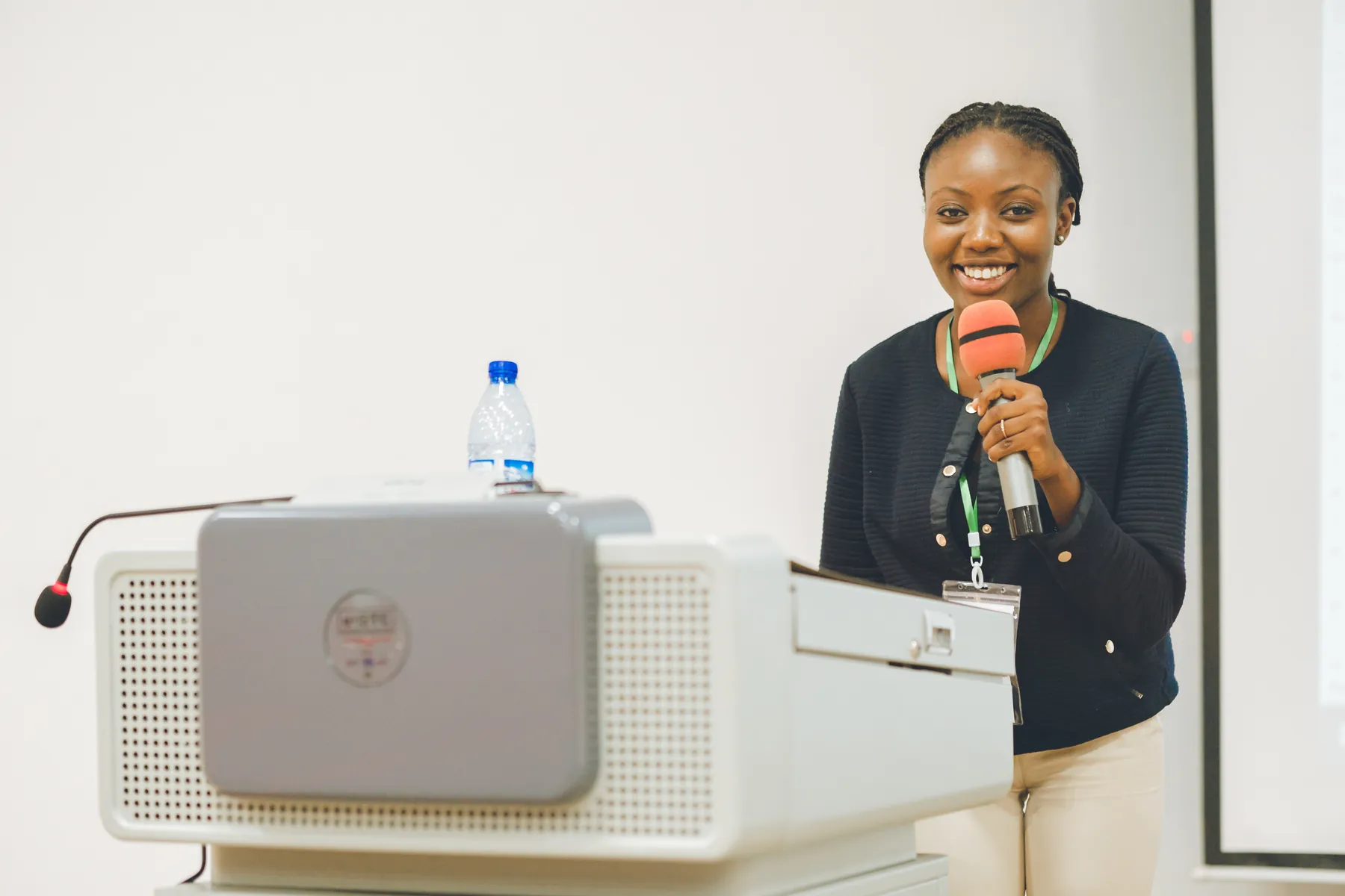 A smiling presenter speaking at a conference lectern